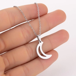 Close-up of a polished silver crescent moon pendant necklace held in hand