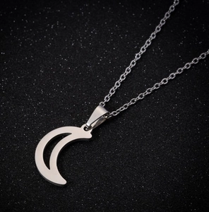 Close-up of polished silver crescent moon pendant necklace on a starry black background