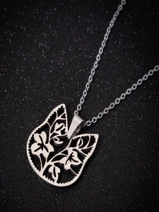 Detailed close-up of hollow butterfly pendant with floral motifs on black background
