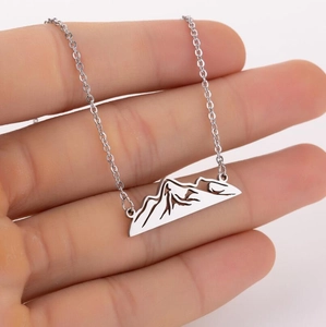Gros plan d'un collier avec pendentif montagne enneigée évidé sur une fine chaîne en argent