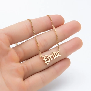 Detailed view of a gold Bride pendant necklace with gothic lettering on a thin chain