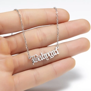 Gros plan du collier avec pendentif Babygirl gothique argenté tenu dans la main