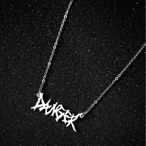 Gros plan du pendentif 'DANGER' gothique en argent sur fond noir texturé avec scintillements