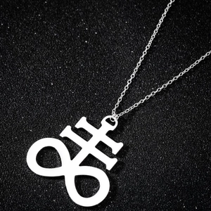 Gros plan du pendentif croix de Léviathan argenté sur une surface noire texturée