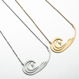 Détail des pendentifs vague ajourés avec silhouette de surfeur en doré et argenté