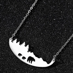 Détail du pendentif ours en acier inoxydable avec silhouettes d'arbres et de forêt