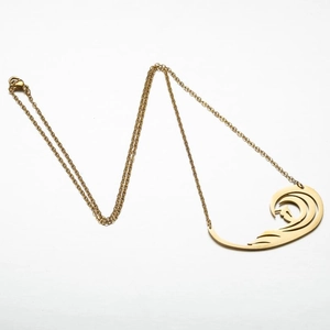 Détail du collier à pendentif vague doré avec découpes artistiques sur fond blanc pur