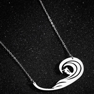 Collier avec pendentif vague de surf en acier inoxydable sur fond noir scintillant