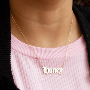 Vintage stainless steel gold necklace with Honey letter pendant worn on a female model