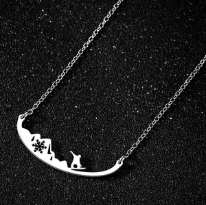 Détail du pendentif montagne argenté avec flocon de neige et motif de snowboarder