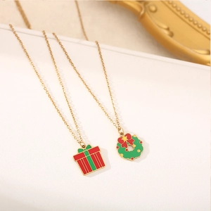 Macro detail of Christmas wreath and gift box pendants on elegant gold steel necklaces