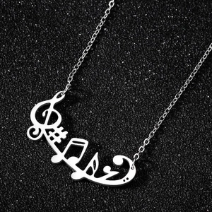 Macro shot of silver music necklace with treble clef and note pendant on black background