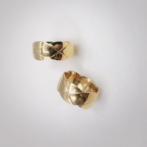 Detailed close-up of wide gold-plated stainless steel rings with quilted diamond pattern
