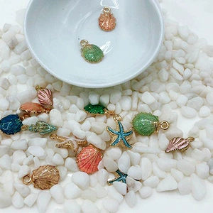 Flat lay of colorful enamel sea shell and starfish charms on white pebbles