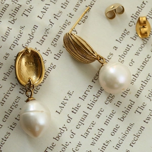 Macro shot of gold-plated freshwater pearl earrings with S925 engraving on vintage book