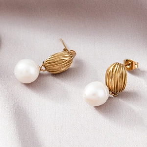 Elegant gold stainless steel earrings with freshwater pearls on a silk texture background