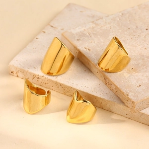 Set of four minimalist wide gold plated stainless steel open rings on a stone surface