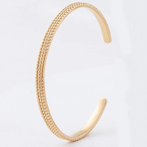Detailed view of gold cuff bracelet featuring a triple-row beaded texture design