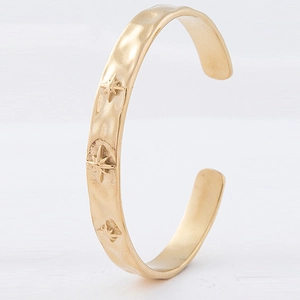 Close-up of vintage gold star-engraved bangle with hammered finish and adjustable opening