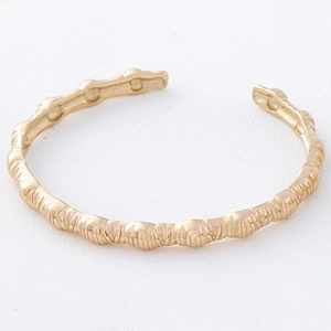 Detailed view of the gold open bangle featuring a unique textured bamboo leaf design