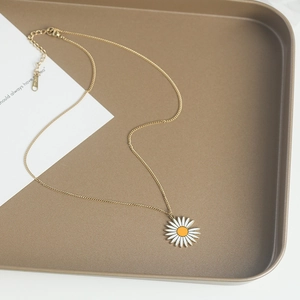 Élégant collier marguerite dorée avec pétales blancs et cœur orange sur un plateau