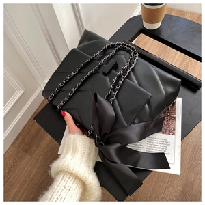 Detail of black chevron quilted shoulder bag with large silk bow and chain strap