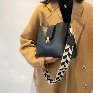 Modern black leather bucket bag with geometric strap and gold twist lock closure
