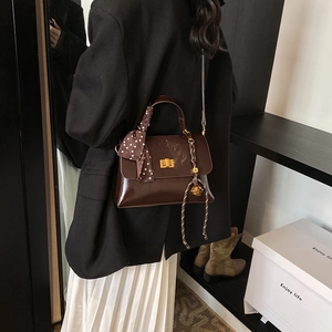 Deep brown leather crossbody bag with silk scarf handle and golden bell charm