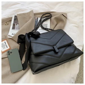 Detail of black V-quilted leather shoulder bag with chain strap and large satin bow
