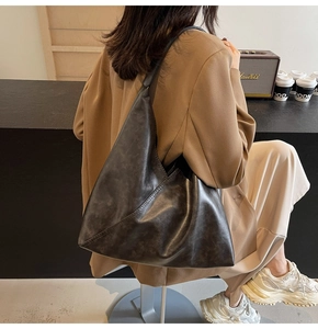 Detailed view of a large vintage leather hobo bag worn by a model in a cozy cafe setting