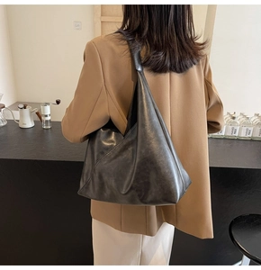 Detailed back view of model wearing a large black soft leather tote bag with wide strap