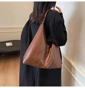 Close-up of a large vintage brown leather tote bag worn with a black blazer