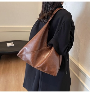 Detailed view of brown retro leather shoulder bag with side stitching and soft texture