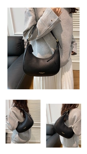 Detail of black pebbled leather crescent underarm bag with gold logo and long strap