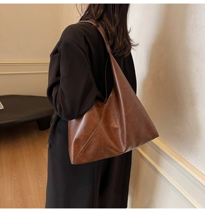 Detail view of large dark brown leather hobo bag worn by model for daily commute