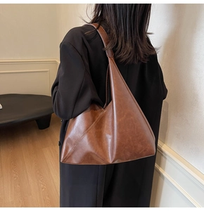 Detailed side view of vintage brown leather tote bag with geometric stitching on model