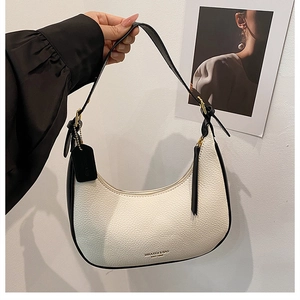 Close-up of beige dumpling bag with black piping and MIKAXIQI & BAG logo lettering