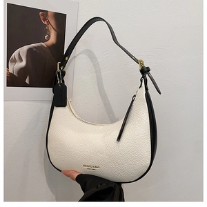 Detail of white lychee leather half-moon bag with black strap and gold hardware