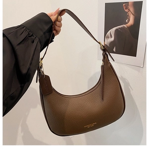 Close-up of brown lychee grain leather dumpling bag with gold logo and hardware details