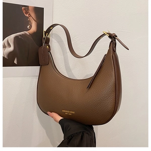 Detail of dark brown leather crescent bag with adjustable strap and gold brand text