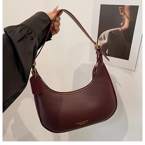 Detail of burgundy lychee grain leather crescent bag with gold zipper and handle