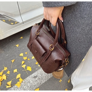 Close-up of deep brown vintage Boston bag with oily leather texture and side buckle pocket