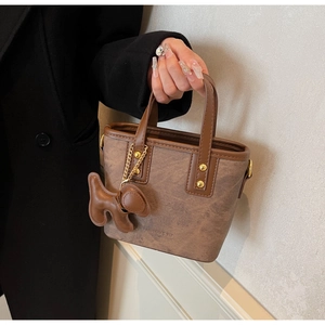 Detail of vintage brown leather tote bag with dog-shaped charm and embossed fashion logo