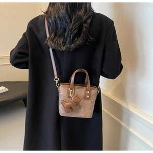 Brown vintage mini bucket bag with leather puppy charm shown on a female model