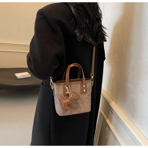 Brown vintage printed mini bucket bag with leather handles and dog charm accessory