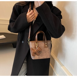 Close-up of vintage brown leather bucket bag with cute dog charm and gold hardware