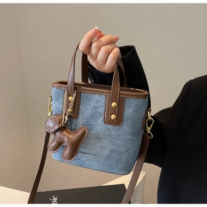 Detail of vintage denim bucket bag with brown leather trim and a cute puppy charm