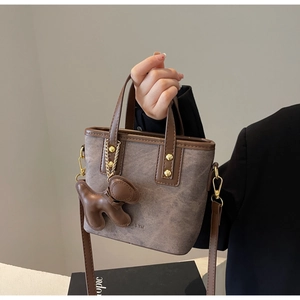 Close-up of retro brown patchwork bucket bag with golden studs and puppy charm