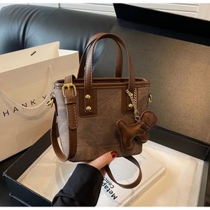 Close-up of vintage brown monogram bucket bag with gold hardware and a cute dog charm