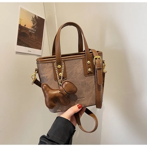 Close-up of canvas bucket bag with brown leather trim and cute dog-shaped charm